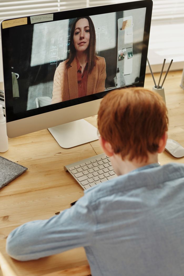 Young boy attending an online class from home using a desktop computer.
